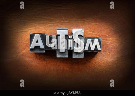 Le mot autisme fait de plomb vintage type typographique sur un fond en cuir. Banque D'Images