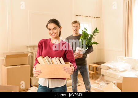 Femme souriante avec des livres et de l'homme tenue à New home Banque D'Images