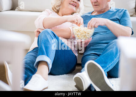 Cropped shot of happy senior couple eating popcorn sur canapé Banque D'Images