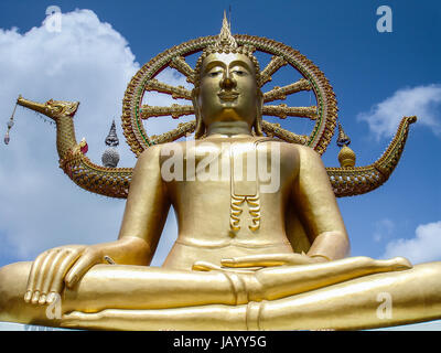 Grand Bouddha assis de Koh Samui, temple Wat Phra Yai en Thaïlande. Ciel bleu avec des nuages épars. le statut de Bouddha Bouddha décrit dans un état de calme et de pureté et de résoudre, après avoir surmonté la tentation et la peur envoyé à lui par Mara, Seigneur de l'illusion. Connu sous le nom de Mara la posture, la main gauche repose paume ouverte et jusqu'à la tour de la statue, la main droite vers le bas sur le genou droit, presque jusqu'au sol Banque D'Images