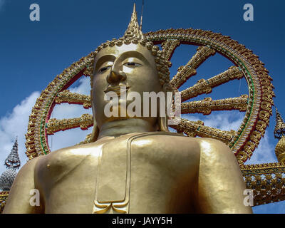 Grand Bouddha assis de Koh Samui, temple Wat Phra Yai en Thaïlande. Ciel bleu avec des nuages épars. le statut de Bouddha Bouddha décrit dans un état de calme et de pureté et de résoudre, après avoir surmonté la tentation et la peur envoyé à lui par Mara, Seigneur de l'illusion. Connu sous le nom de Mara la posture, la main gauche repose paume ouverte et jusqu'à la tour de la statue, la main droite vers le bas sur le genou droit, presque jusqu'au sol Banque D'Images