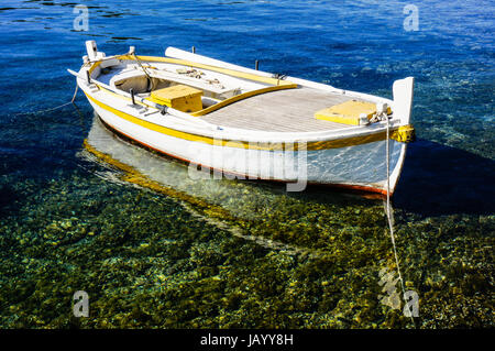 Petit bateau de pêche est clairement un ancrage dans les eaux peu profondes. le bateau est en réflexion dans l'eau. Banque D'Images