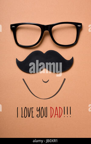Une moustache et une paire de lunettes formant la face d'un homme sur un fond orange et le texte que j'aime papa Banque D'Images