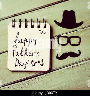 Un carnet à spirales avec le texte heureux pères jours écrits en C et d'une moustache, une paire de lunettes et un chapeau formant la face d'homme, on a rustic Banque D'Images
