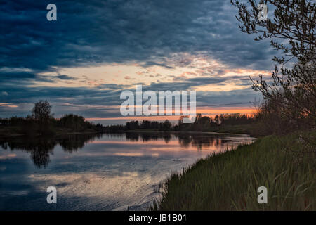 Le soleil se couche tard dans l'été au nord de la Finlande. La lumière du coucher de soleil reflète magnifiquement sur l'eau de la rivière. Banque D'Images