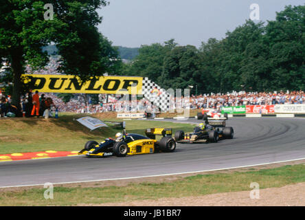 1986 British GP à Brands Hatch. Andrea De Cesaris sur Minardi M85B sur le point d'être léché par Ayrton Senna en Lotus JPS 98T. Banque D'Images