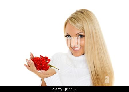 Les jeunes professionnels belle femme pull en laine en hiver avec une poignée de fruits rouges sur un fond blanc. Banque D'Images