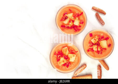 Une photo d'un salmorejo, soupe froide espagnole traditionnelle, servie dans des verres avec des bâtonnets de pain, garnie de jambon et croûtons, tourné par le haut avec un Banque D'Images