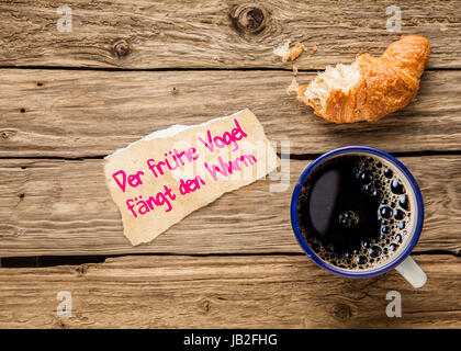 Der frÃ¼he Vogel fÃ¤ngt den Wurm - prolongiez - un message sur un bout de papier déchiré un petit-déjeuner plus tôt alonside de café expresso et à moitié mangé un croissant Banque D'Images