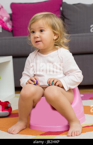 Petite fille assise sur le pot à la maison. Banque D'Images