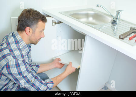 Jeune homme de plombier dans la salle de bains lavabo fixation Banque D'Images