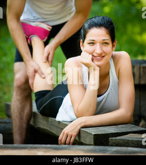 Massage homme donne de veau à jeune femme après le jogging Banque D'Images