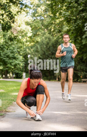 Jeune femme sport lacet, liant l'homme à l'origine est le jogging Banque D'Images