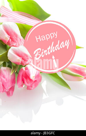 Joli Joyeux Anniversaire féminin avec un message d'ambiance festive et rosette rose un bouquet de belles tulipes roses fraîches sur un fond blanc, perspective gros plan Banque D'Images