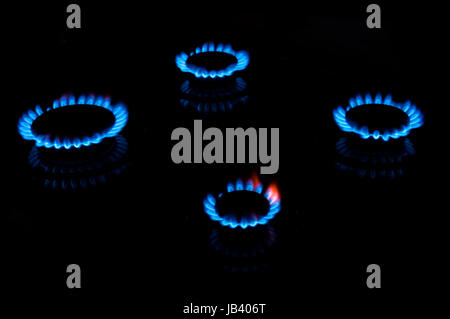 Les flammes bleues de quatre brûleurs cuisinière dans le noir Banque D'Images