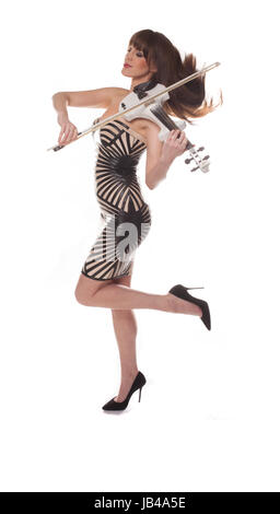 Femme élégante de style moderne dans une robe moulante et talons jouant du violon tout en rejetant ses longs cheveux brune et en équilibre sur un pied, isolated on white Banque D'Images