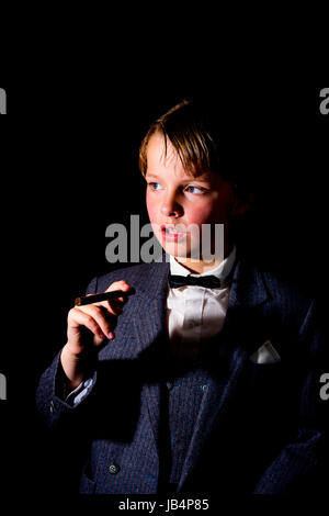 Boy in suit, tenant un cigare. faible image clé. Banque D'Images