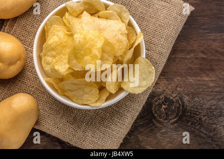 Une photo d'un bol de croustilles de pommes de terre, tourné à partir de ci-dessus sur la texture rustique foncé, avec une place pour le texte Banque D'Images