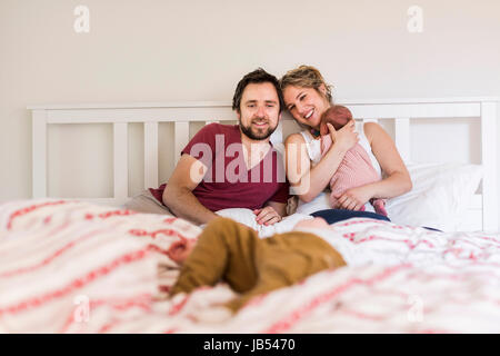 Les jeunes parents dans le lit avec leurs petits enfants Banque D'Images