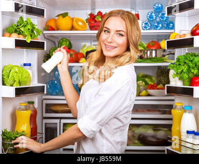 Femme choisi de lait dans le réfrigérateur ouvert, cool nouveau friedge plein de nutrition biologique savoureuse, femme la préparation à cuire, concept de saine alimentation Banque D'Images