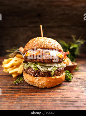 Fresh burger avec fromage, viande et légumes sur fond de bois Banque D'Images