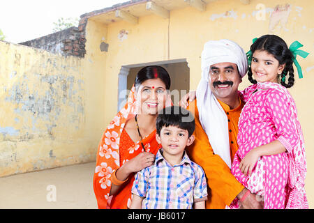 Les parents ruraux indiens et leurs deux enfants debout devant la maison familiale dans le village de l'Haryana Banque D'Images