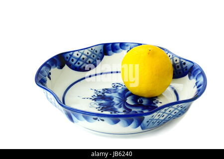 Vase en céramique blanche pour des bonbons et des fruits quadrangulaires. C'est peint avec un motif bleu-bleu dans le style Gzhel et un citron. Banque D'Images