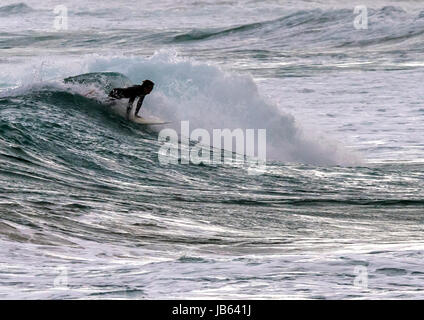 Lone surfer en essayant d'attraper une vague dans l'état de la mer Banque D'Images