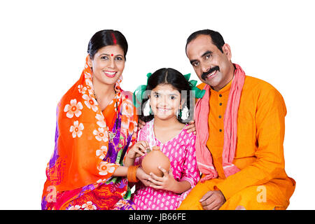 Heureux de la famille rurale indienne- Parents et enfant fille assis ensemble et mettre Coin Tirelire d'économiser de l'argent Banque D'Images