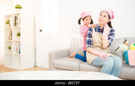 Heureux les enfants chinois asiatique fille aider massage femme fatiguée et de faire le nettoyage dans la salle de séjour ensemble à la maison. ménage ménage et concept. Banque D'Images
