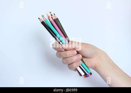 Une main remplie de crayons de couleur sur fond blanc Banque D'Images