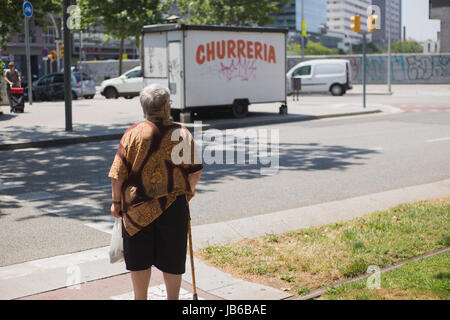 Femme attendant de traverser la route dans la région de Diagonal Mar de Barcelone. Banque D'Images