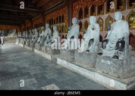 Homme qui prie par rangée de statues Arhat, Bai Dinh Buddist Temple complexe, près de Ninh Binh, Vietnam Banque D'Images