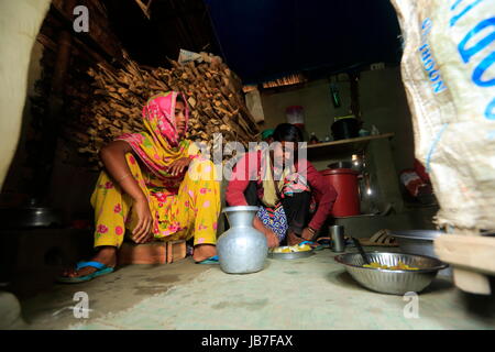 Une femme prendre repas dans sa petite hutte près de brickfield. Banque D'Images