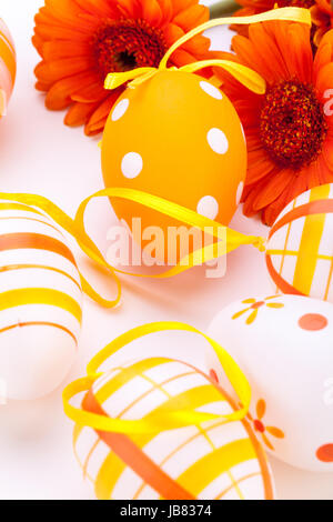Traditionnelle bemalte bunte ostereier mit orangen karte frohe ostern dekoration gerbera isoliert textfreiraum Banque D'Images