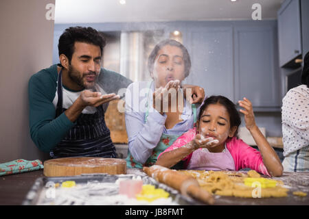 Famille ludique soufflant de la farine en cuisine à la maison Banque D'Images