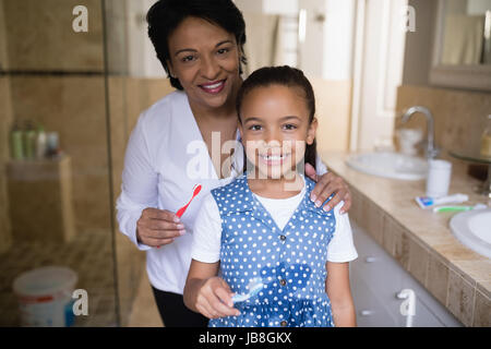 Portrait of smiling girl holding grand-mère avec des brosses à dents dans la salle de bains Banque D'Images