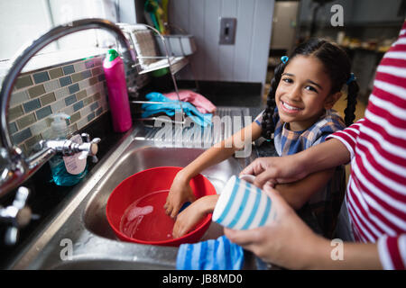 Portrait of cute smiling girl aider sa mère dans la cuisine à la maison Banque D'Images