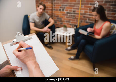 Part de l'exécutif writing on clipboard in office Banque D'Images