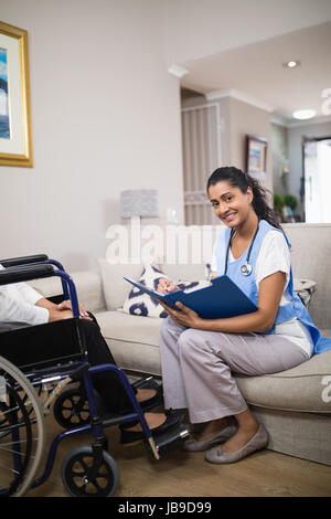 Portrait of smiling young doctor checking patient rapport médical à la maison Banque D'Images