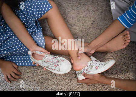 Portrait de Mère fille aidant à porter ses chaussures à la maison Banque D'Images