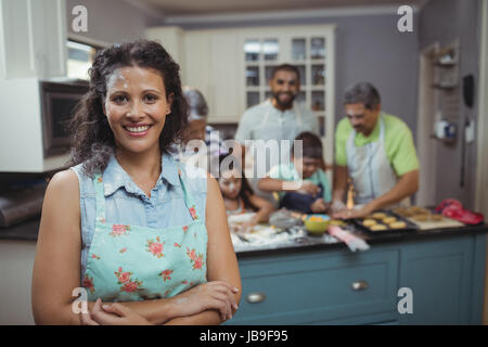 Woman smiling at camera while preparing dessert les membres de la famille en arrière-plan à la maison Banque D'Images