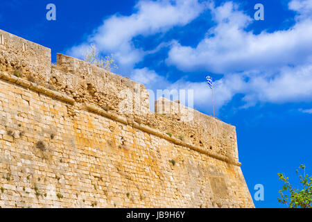 Drapeau grec vole sur un mât à la tour de château Fortezza - forteresse Vénitienne sur Paleokastro hill resort à Réthymnon. L'architecture grecque sur la côte de Ko Banque D'Images