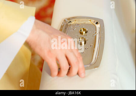 Chrome visible plateau avec deux anneaux de mariage et de gouttes d'eau bénite pendant la cérémonie du mariage dans cahtolic l'église. Figure méconnaissable, modèle libération pas nécessaire. Banque D'Images