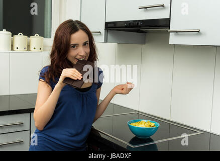 Jeune femme est de mordre un morceau de chocolat noir avec un sourire. Banque D'Images