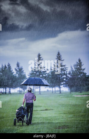 Golfeur sur un jour de pluie laissant le golf (le jeu est annulé à cause de la tempête) Banque D'Images