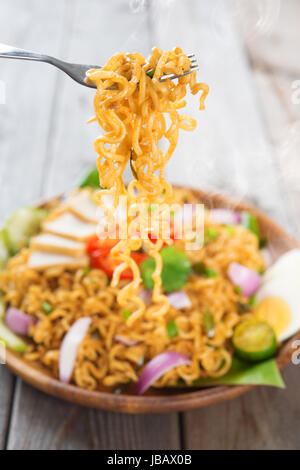 Frit épicé curry nouilles instantanées ou style Malaisien maggi goreng mamak. Prêt à servir sur table à manger en bois. Douce chaude avec de la fumée. Banque D'Images