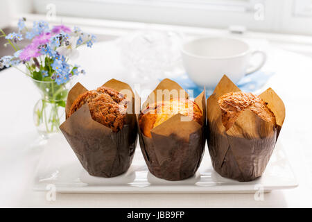 Table du petit déjeuner avec trois muffins dans les moules en papier brun Banque D'Images