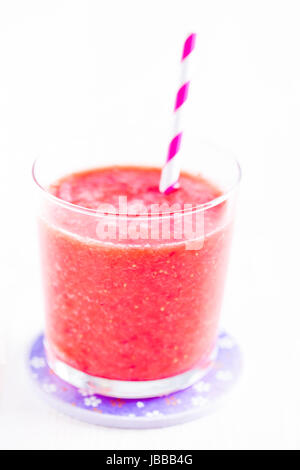 Smoothie aux fraises et de paille à rayures en verre sur la plaque pourpre Banque D'Images