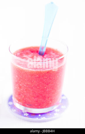 Smoothie aux fraises de gros plan et cuillère en plastique bleu sur la plaque en verre violet Banque D'Images